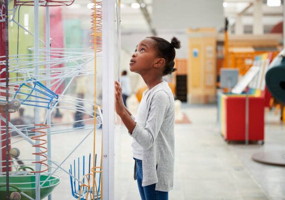 Young black girl looking at a science exhibit, close up
