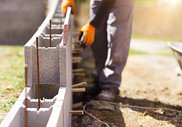 Bricklayer putting down another row of bricks in site