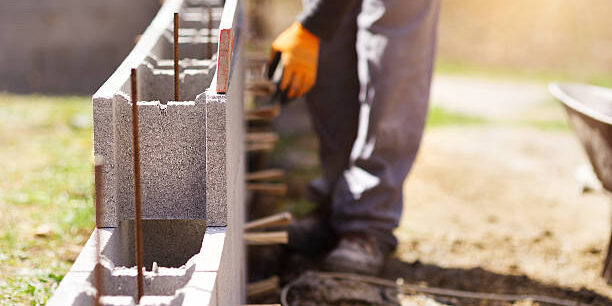 Bricklayer putting down another row of bricks in site