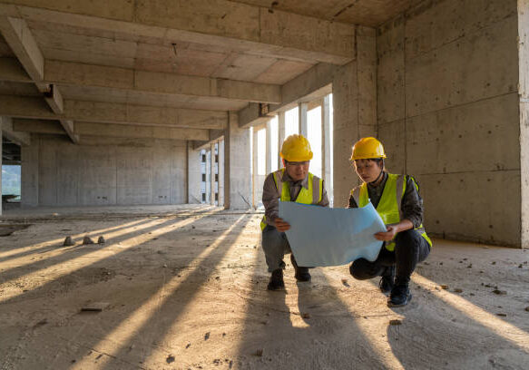 Male and female construction engineers with drawings comparing data