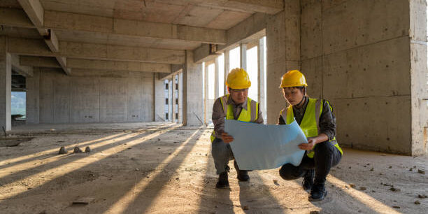 Male and female construction engineers with drawings comparing data