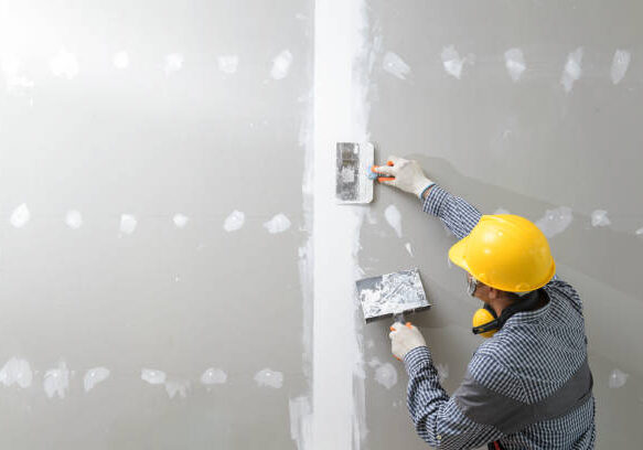 interior decoration construction furniture builtin.Plasterer in working uniform plastering the wall indoors.