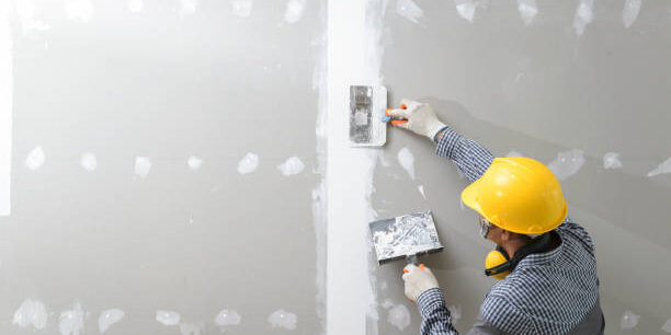 interior decoration construction furniture builtin.Plasterer in working uniform plastering the wall indoors.