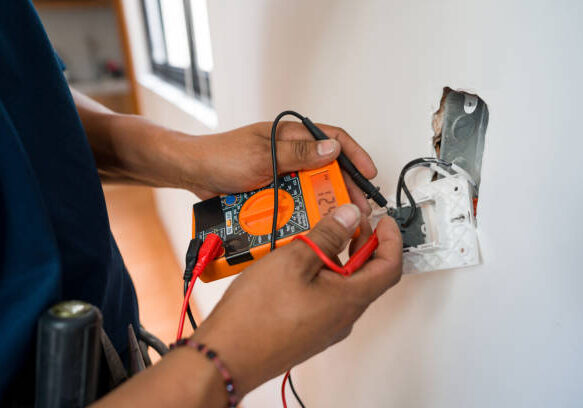 Close-up on an electrician fixing an electrical outlet and measuring the voltage at a house - home improvement concepts