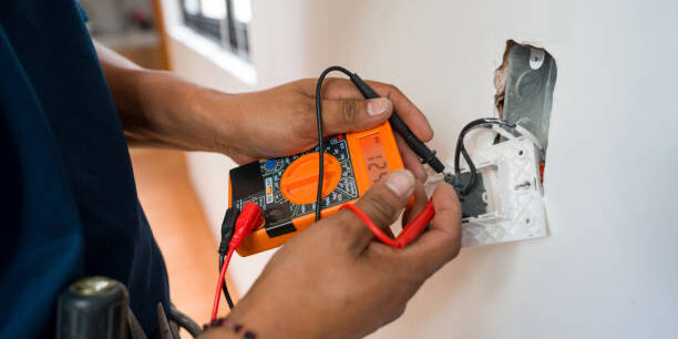 Close-up on an electrician fixing an electrical outlet and measuring the voltage at a house - home improvement concepts