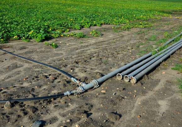 irrigation pipes in the field. water is pumped from the river and through large diameter metal pipes is led to polis melons and gourds. growing vegetables at high yield