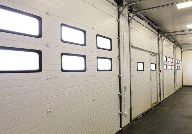 Row of overhead sectional doors in a multi-seat car garage. Inside view.