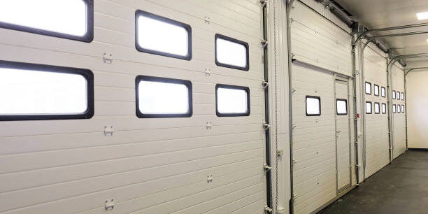 Row of overhead sectional doors in a multi-seat car garage. Inside view.